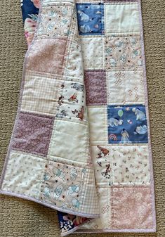 two baby quilts laying on the floor next to each other, one is pink and blue