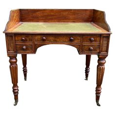 an old wooden desk with two drawers on one side and a green cloth top on the other