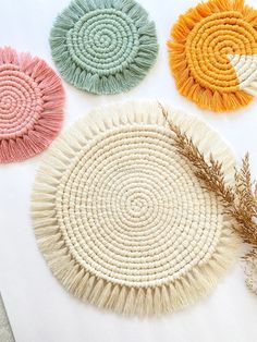 four woven coasters with different colors and patterns on top of a white tablecloth