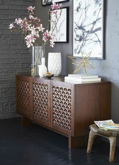 a vase with flowers sitting on top of a wooden sideboard next to a wall