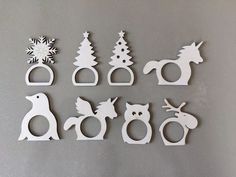 twelve wooden cutouts of christmas trees, animals and snowflakes on a gray surface