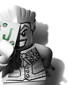 a black and white photo of a lego man holding a piece of paper with the letter j on it