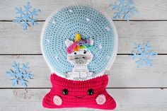 a crocheted snow globe with a llama in the center and blue snowflakes around it