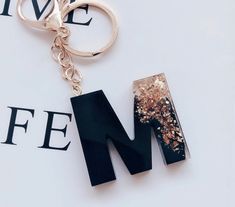 the letter m is made up of black letters and gold glitters on it's sides