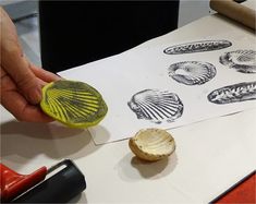 a person is stamping shells on paper with a yellow rubber seal and some glue