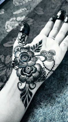 a woman's hand is decorated with hennap and black flowers on it