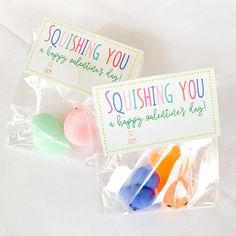 two packaged candy lollipops sitting on top of a white sheeted surface