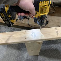 a person using a power drill to attach a piece of wood on top of a bench