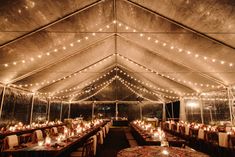 the inside of a tent with tables and chairs set up for dinner under string lights