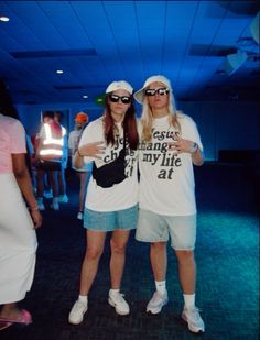 two people standing next to each other wearing sunglasses and t - shirts with words on them