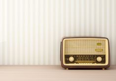 an old fashioned radio sitting on top of a wooden table next to a striped wall