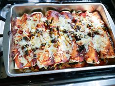 a metal pan filled with pizza covered in cheese and toppings on top of a stove