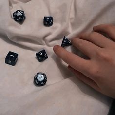 a person holding their hand over some dices on a bed with white sheets behind them