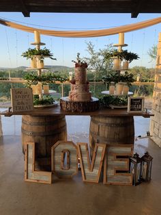 a wedding cake on top of barrels with the word love spelled out