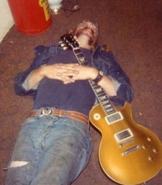 a man laying on the floor next to a guitar