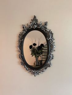 there is a mirror on the wall with flowers in it