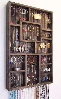 a wooden shelf filled with lots of different types of jewelry hanging on it's sides