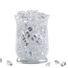 a glass jar filled with lots of ice and silver balls on top of white background