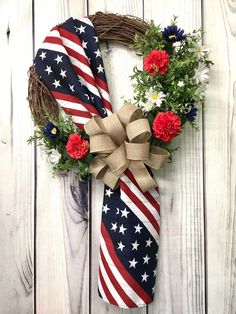 a patriotic wreath with flowers and an american flag tie hanging on a white wooden wall