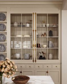 a dining room table with plates and vases on it's shelf next to a china cabinet