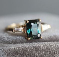 an emerald colored ring with two baguettes on it