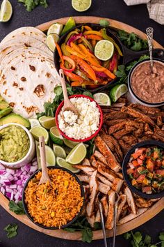 a platter filled with tacos, salsa, and other foods on a table