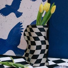 yellow tulips are in a black and white vase