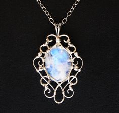 This stunningly elegant pendant necklace is handcrafted from sterling silver and a gorgeous rainbow moonstone cabochon, with lovely flashes of blue color. Pendant comes with an Italian made .925 sterling silver chain with lobster clasp (see photos) in your choice of length. Generously sized bail allows you to swap out different chain styles, if desired. One of a kind pendant measures approximately 2 inches long by 1.25 inches wide, and will come beautifully gift boxed, as shown in last photo. Sh Handmade Moonstone Jewelry In White Gold, Handmade White Gold Moonstone Jewelry, Elegant Hand Forged Moonstone Jewelry, Oval Moonstone Wire Wrapped Jewelry, Moonstone Pendant Necklace, Harpers Ferry, Broken China Jewelry, Rainbow Moonstone Pendant, China Jewelry