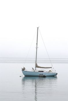 a sailboat floating in the water on a foggy day