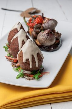 some food is sitting on a white plate with yellow napkins and a yellow cloth