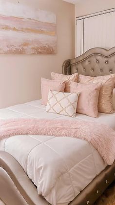 a bed with pink and white pillows on it in a bedroom next to a painting