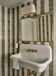 a white sink sitting under a bathroom mirror next to a wall mounted faucet