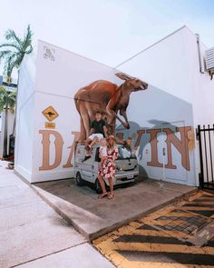 two women are standing in front of a wall with an image of a cow on it