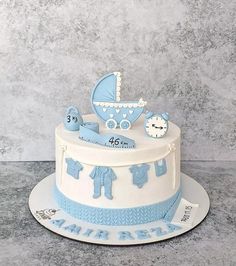 a blue and white cake with a baby's carriage on top, sitting on a table