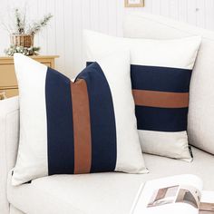 two pillows sitting on top of a white couch next to a table with a book