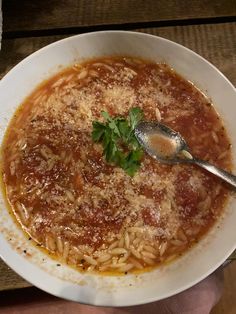 a bowl of pasta with parmesan cheese on top and a spoon in it