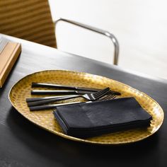 a yellow plate topped with black napkins on top of a table