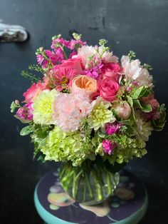 a vase filled with lots of pink and green flowers on top of a blue table