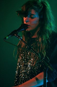 a woman standing in front of a microphone on top of a stage with her eyes closed