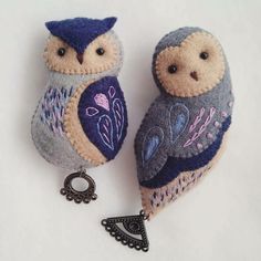 two stuffed owls sitting next to each other on top of a white surface with a keychain