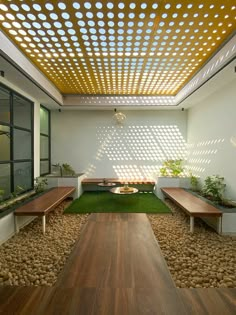 a room with wooden benches and grass in the center is lit by sunlight streaming through the ceiling