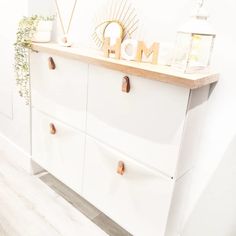 a white dresser with the word mom on it and some plants in front of it