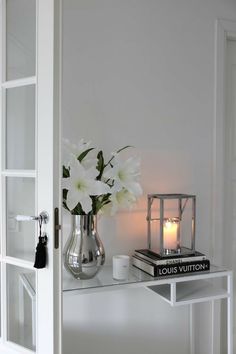 a vase filled with white flowers sitting on top of a table next to a candle