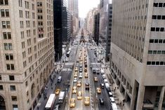 a city street filled with lots of traffic next to tall buildings on either side of the road