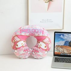 a laptop computer sitting on top of a desk next to an inflatable hello kitty pillow