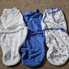 three baby swaddles laying on the floor next to each other, all in blue and white