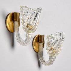 two glass wall lights mounted to the side of a wall