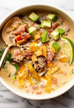 a white bowl filled with soup and topped with avocado