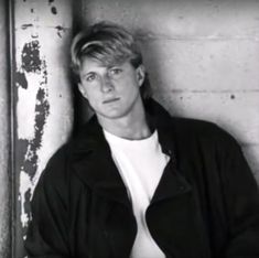 black and white photograph of a man leaning against a wall