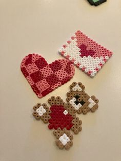 three pieces of bead art sitting on top of a white table next to each other